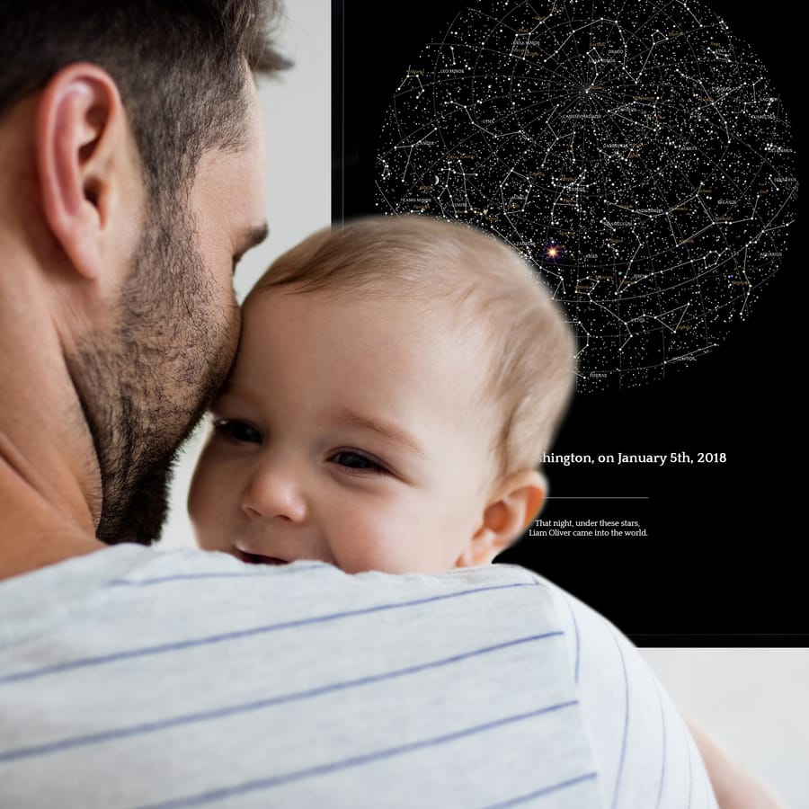 Un jeune papa avec un bébé devant la carte des étoiles commémorant la naissance du bébé
